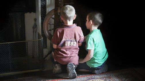 Two children looking at the mouse hole in Beatrix Potter's Hill Top, Lake District